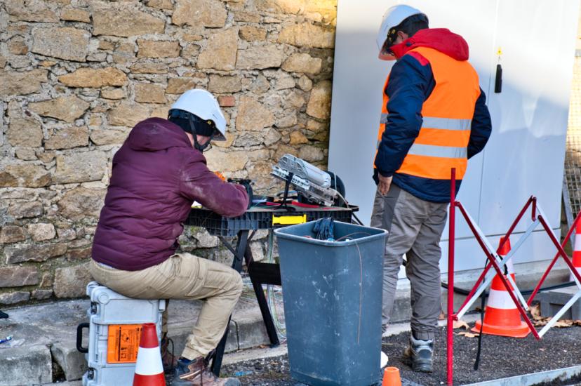 Workers in hard hats and high vis clothing installing fibre optics cables for communications - image is set in France but to represent Germany copper network shutdown